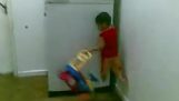 Little boy climbs a fridge with one hand