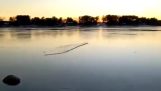 Kaster et stykke is på en frossen innsjø