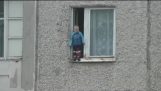 One child 2 years old standing on the edge of the window on the 8th floor