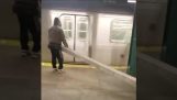 El hombre tratando de llevar a un poste de metal en metro