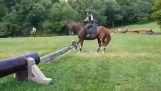 Tilbageholdende med hesten springer en forhindring