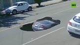 cae coche en un gran agujero en la carretera (Brasil)