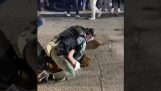 Der Polizist beruhigt einen jungen Mann während eines Streits