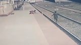 A railway employee rescues a child from a passing train