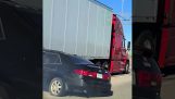 Vrachtwagen rijdt met auto onder aanhanger