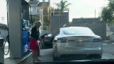De blonde met de elektrische auto bij het benzinestation